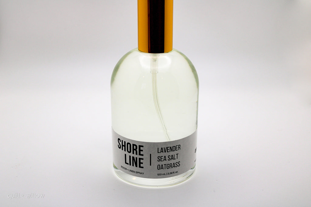 Clear bottle with a gold cap labeled 'Shore Line' room spray on a white background