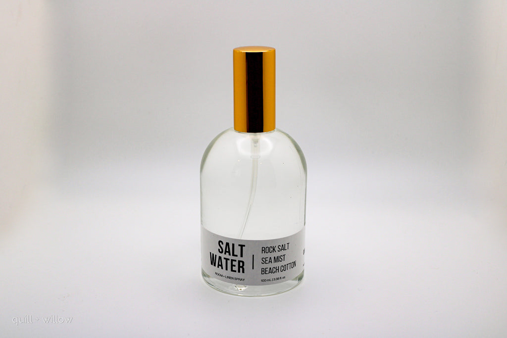 Clear bottle labeled 'Salt Water' with a gold cap on a light gray background