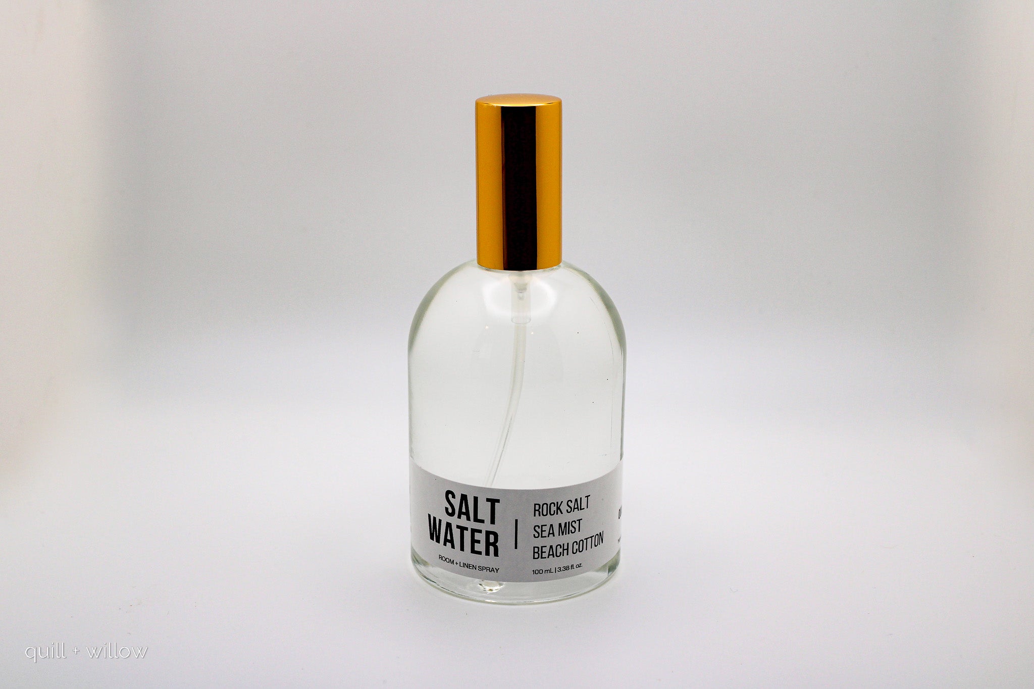 Clear bottle labeled 'Salt Water' with a gold cap on a light gray background