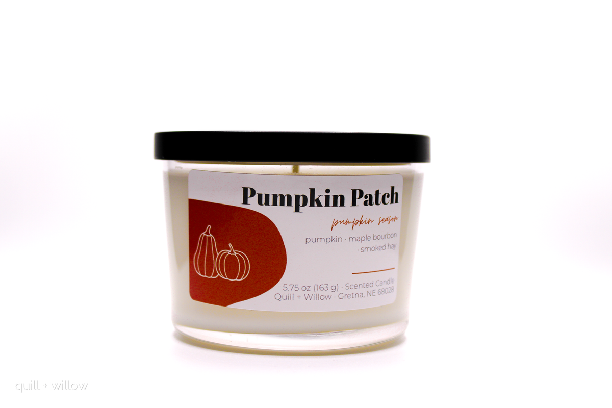 A jar candle labeled 'Pumpkin Patch' with a black lid and white wax, photographed on a clean white background.