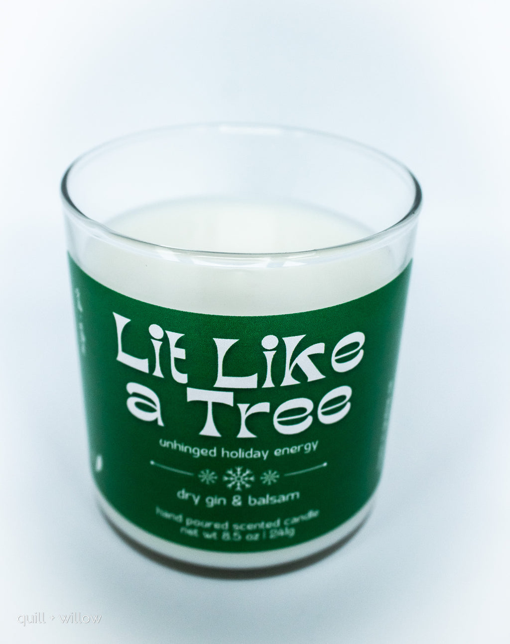 Candle with a green label reading 'Lit Like a Tree' on a white background