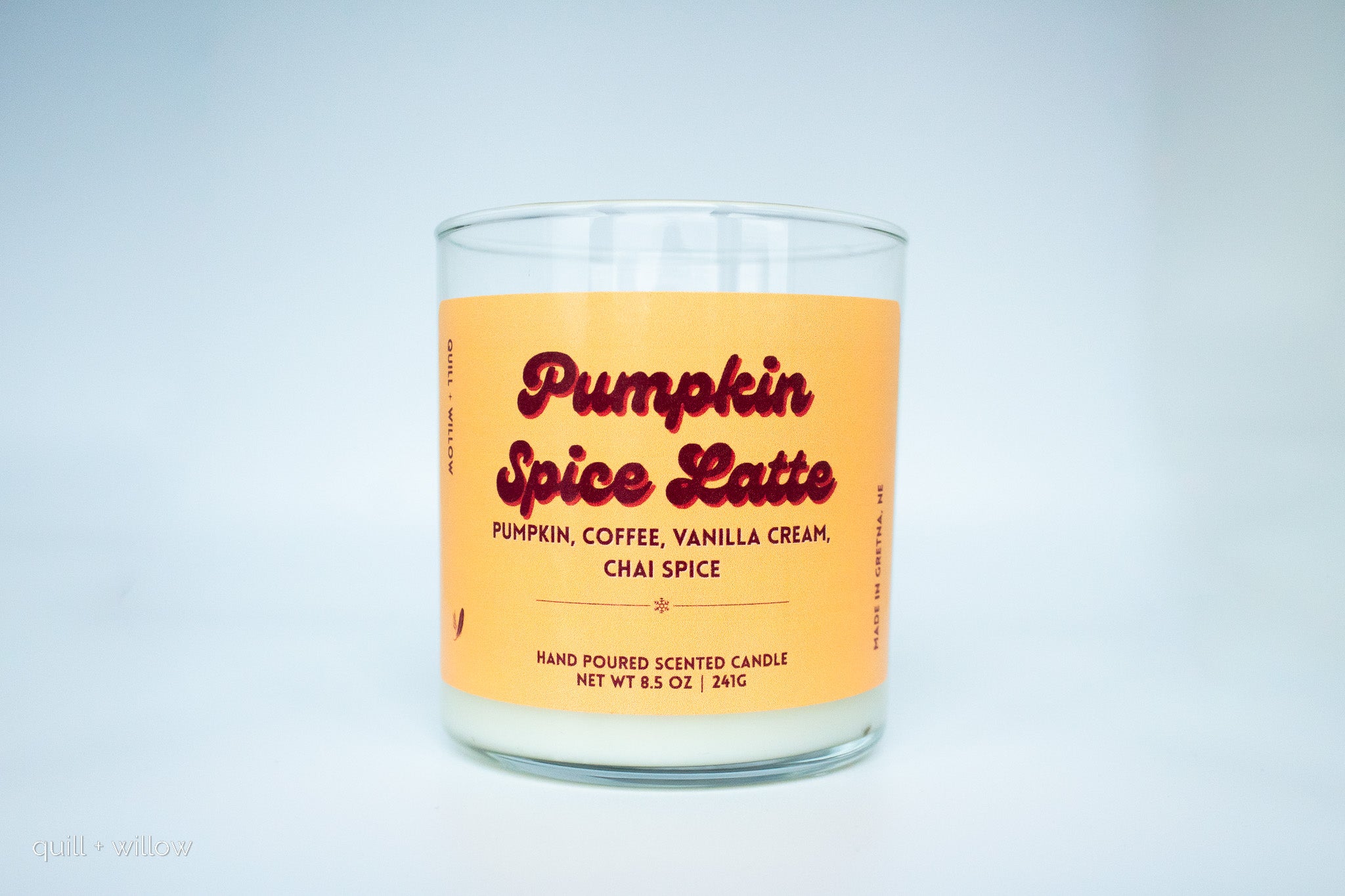 Candle with a pumpkin spice latte label on a light gray background