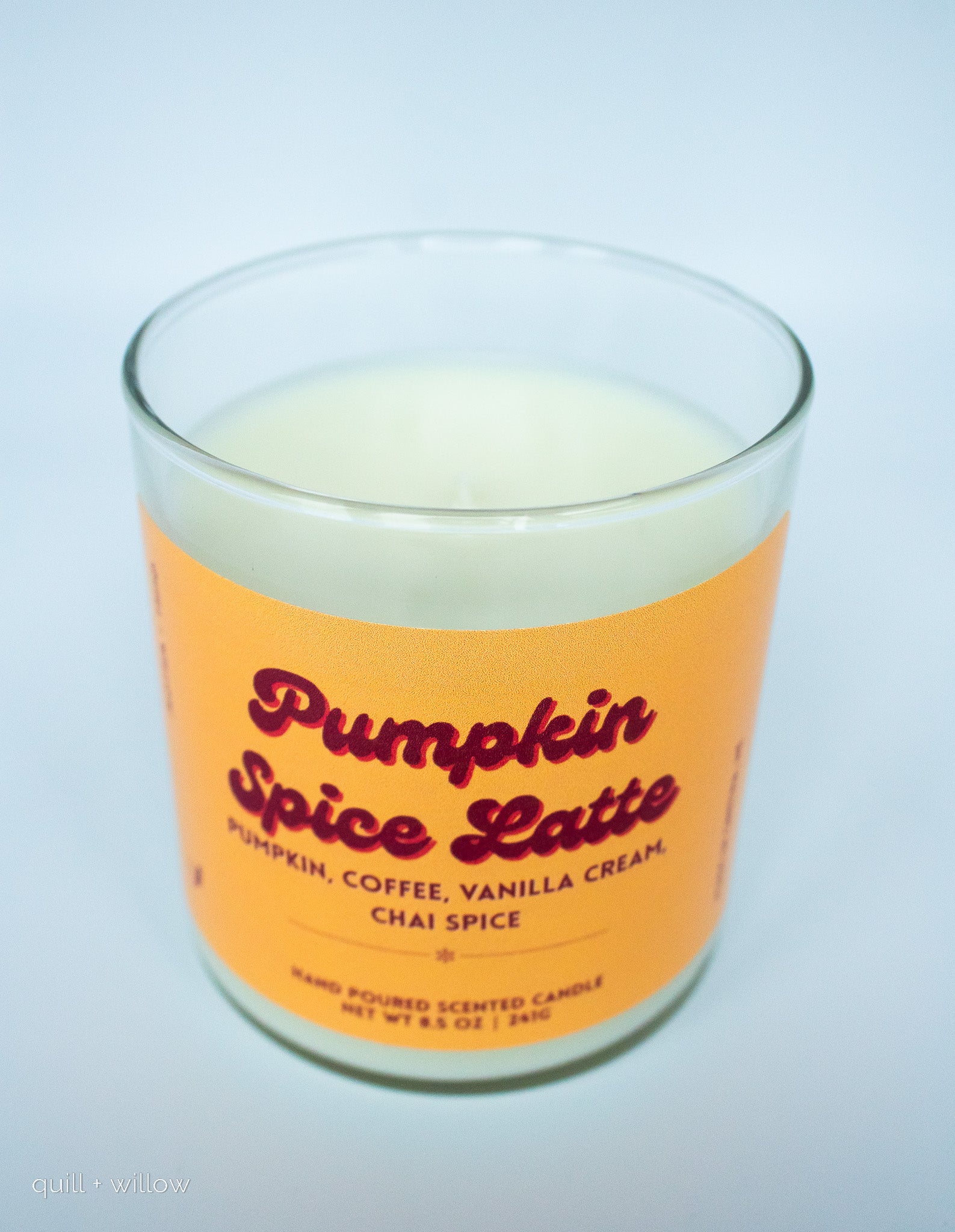 Candle with 'Pumpkin Spice Latte' label on an orange background