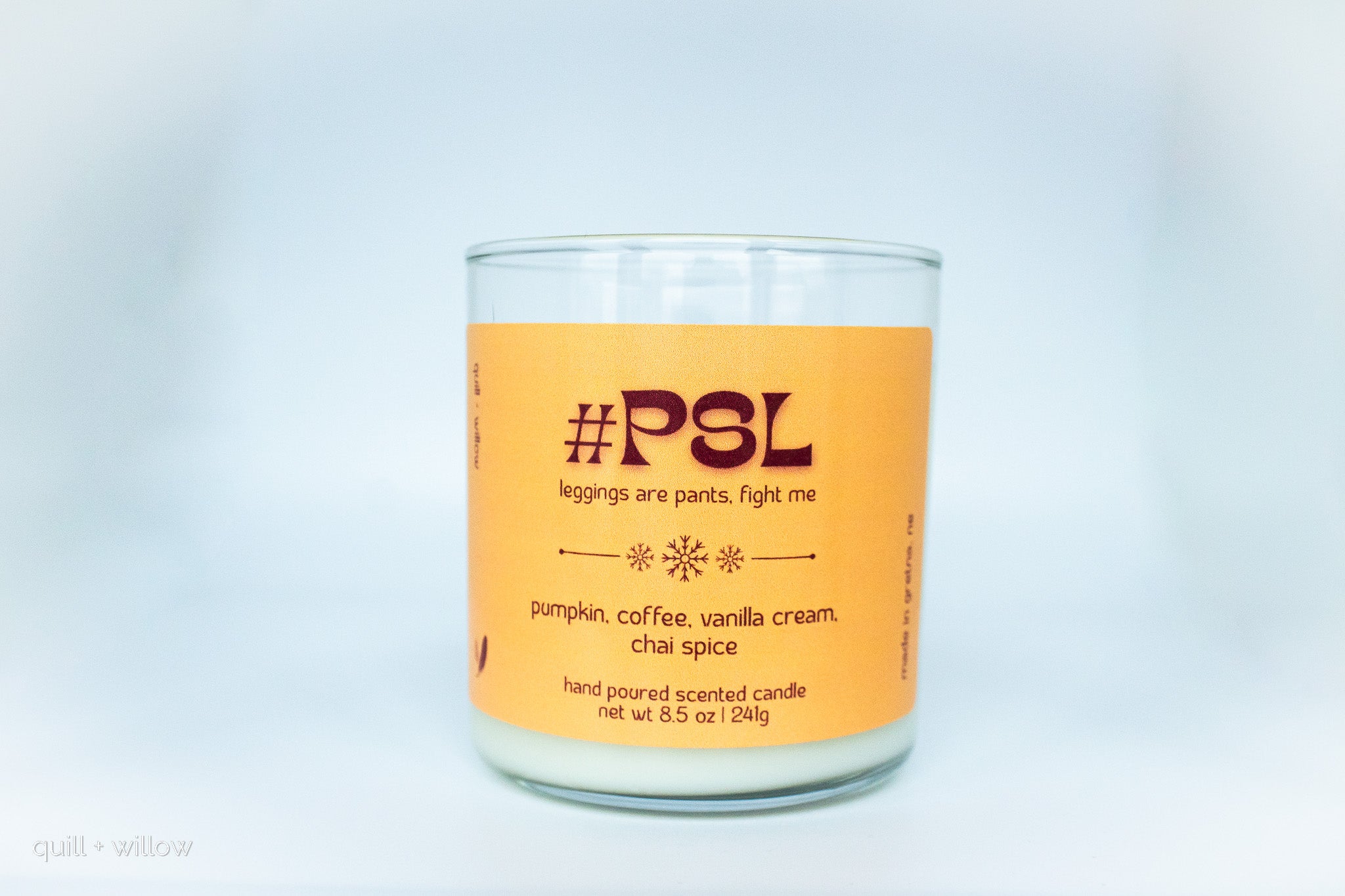 Scented candle with an orange label on a light gray background