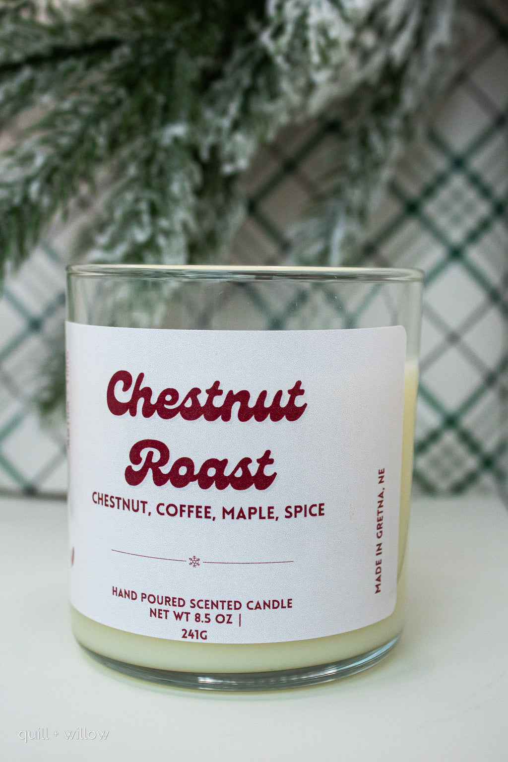 Candle labeled 'Chestnut Roast' with a Christmas tree and plaid fabric in the background
