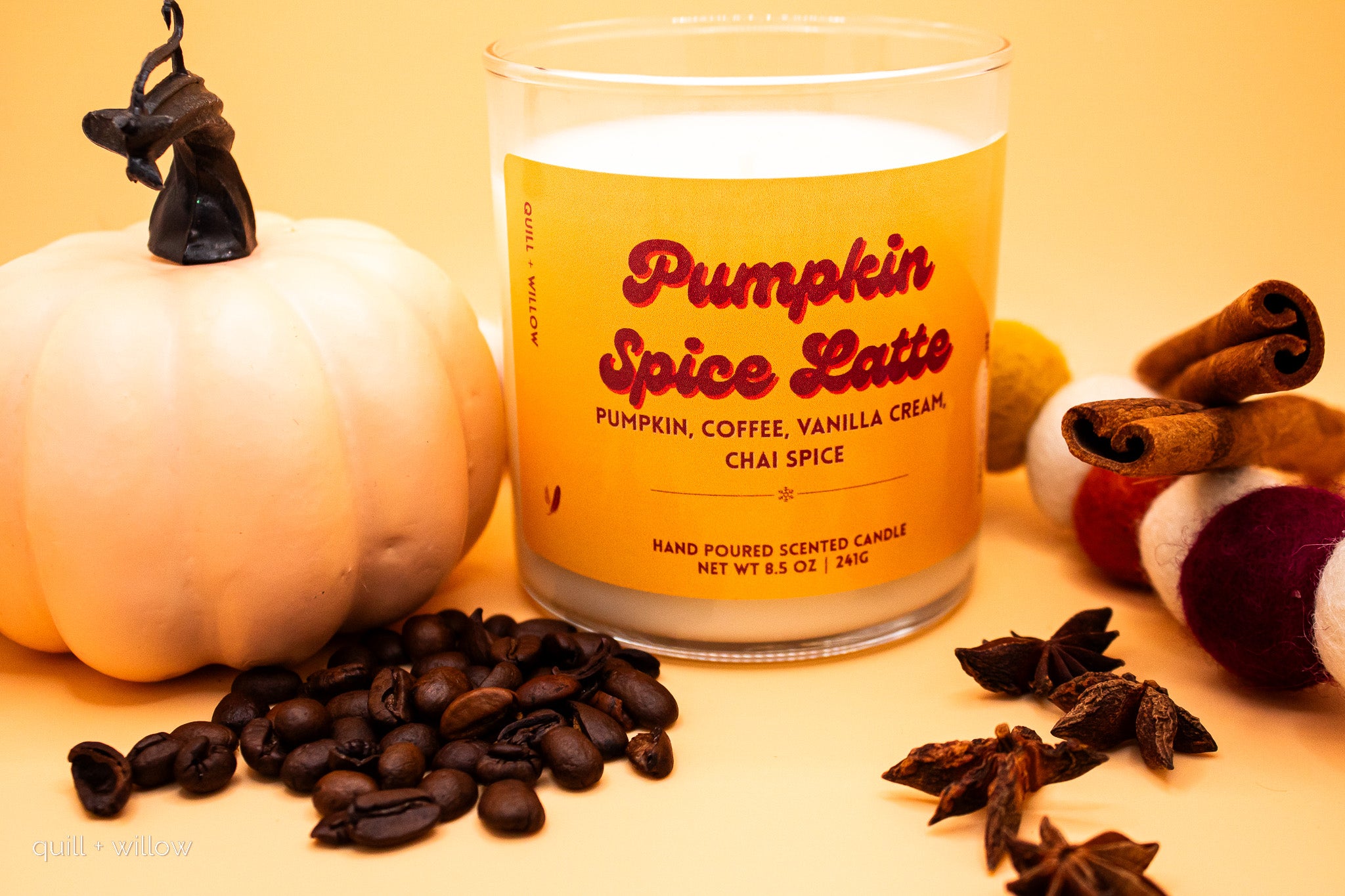 Candle labeled 'Pumpkin Spice Latte' with pumpkins, coffee beans, and cinnamon sticks on a yellow background