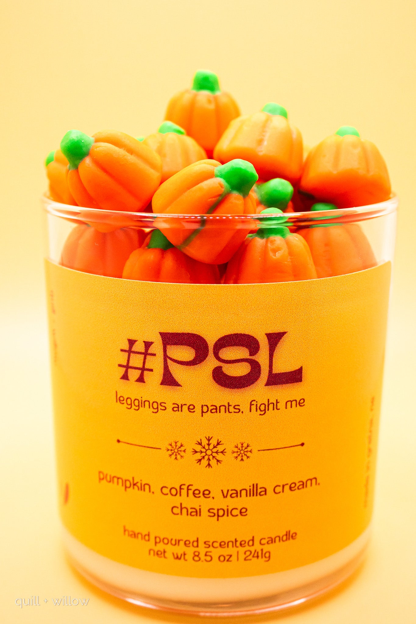 Pumpkin-shaped candles in a container with text on a yellow background