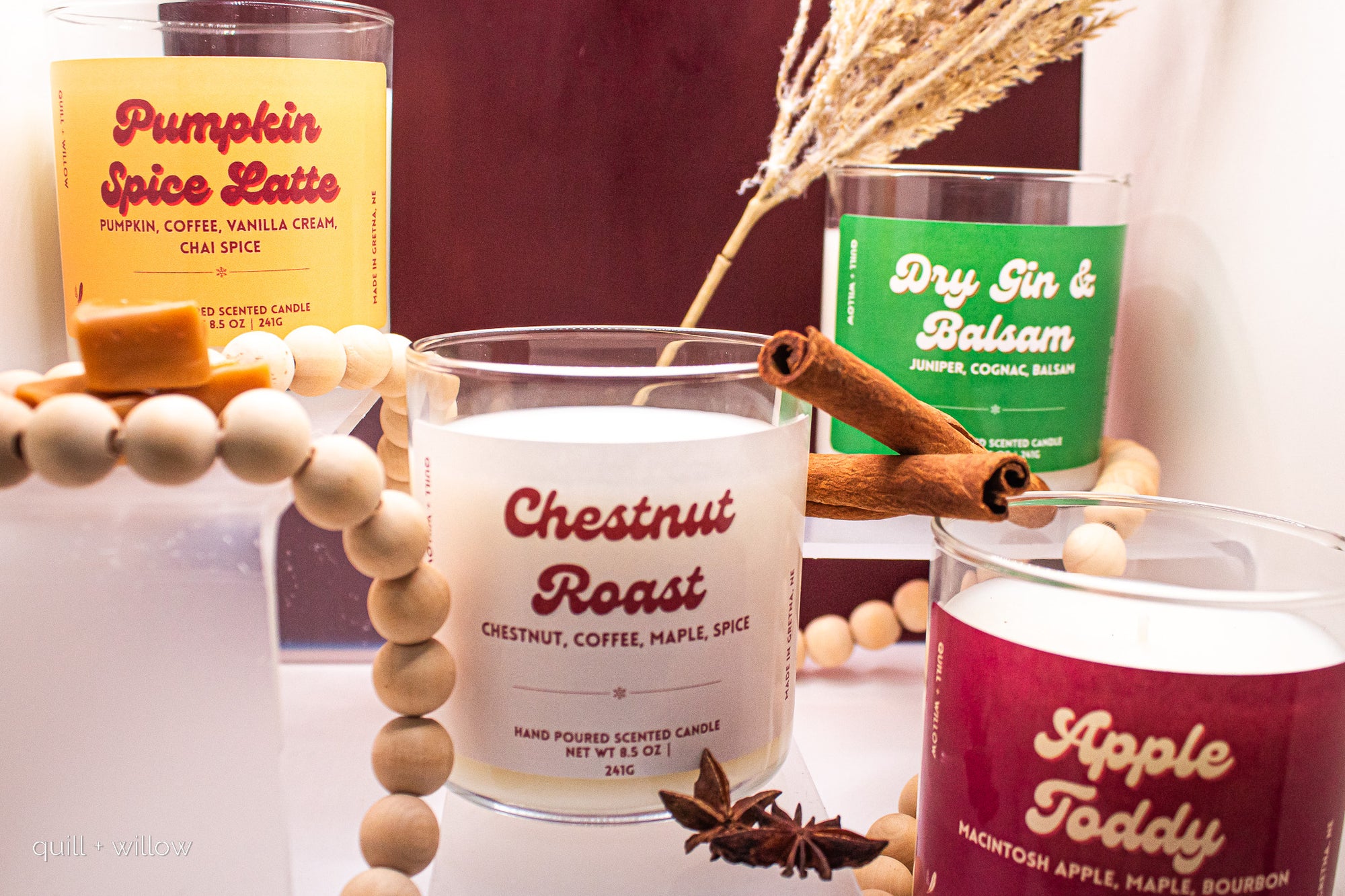 Candles with labels 'Pumpkin Spice Latte', 'Dry Gin & Balsam', and 'Apple Toddy' on a decorative surface.
