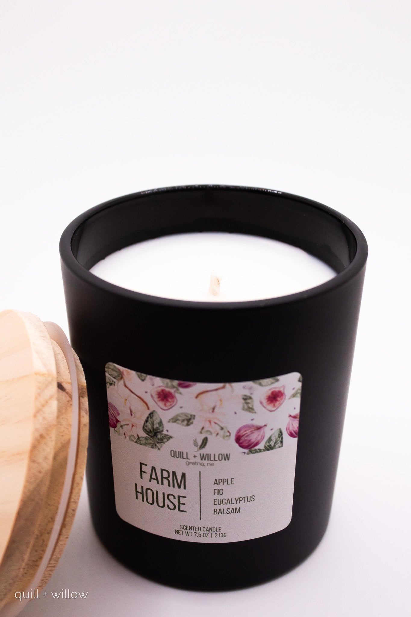 Black candle with a floral label on a white background