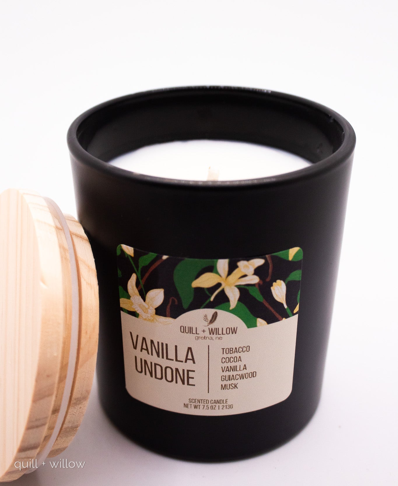 Black candle with a floral label on a white background