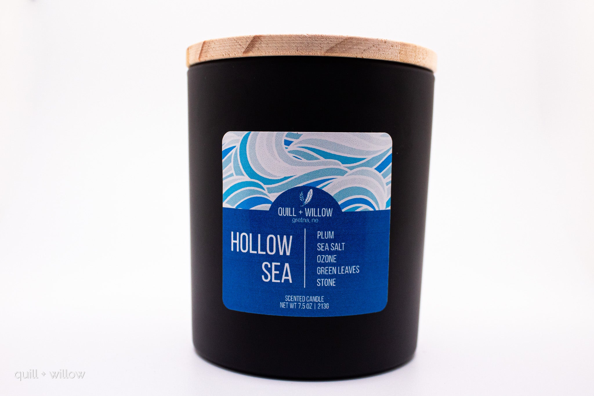 Black candle with a wooden lid and blue label on a white background