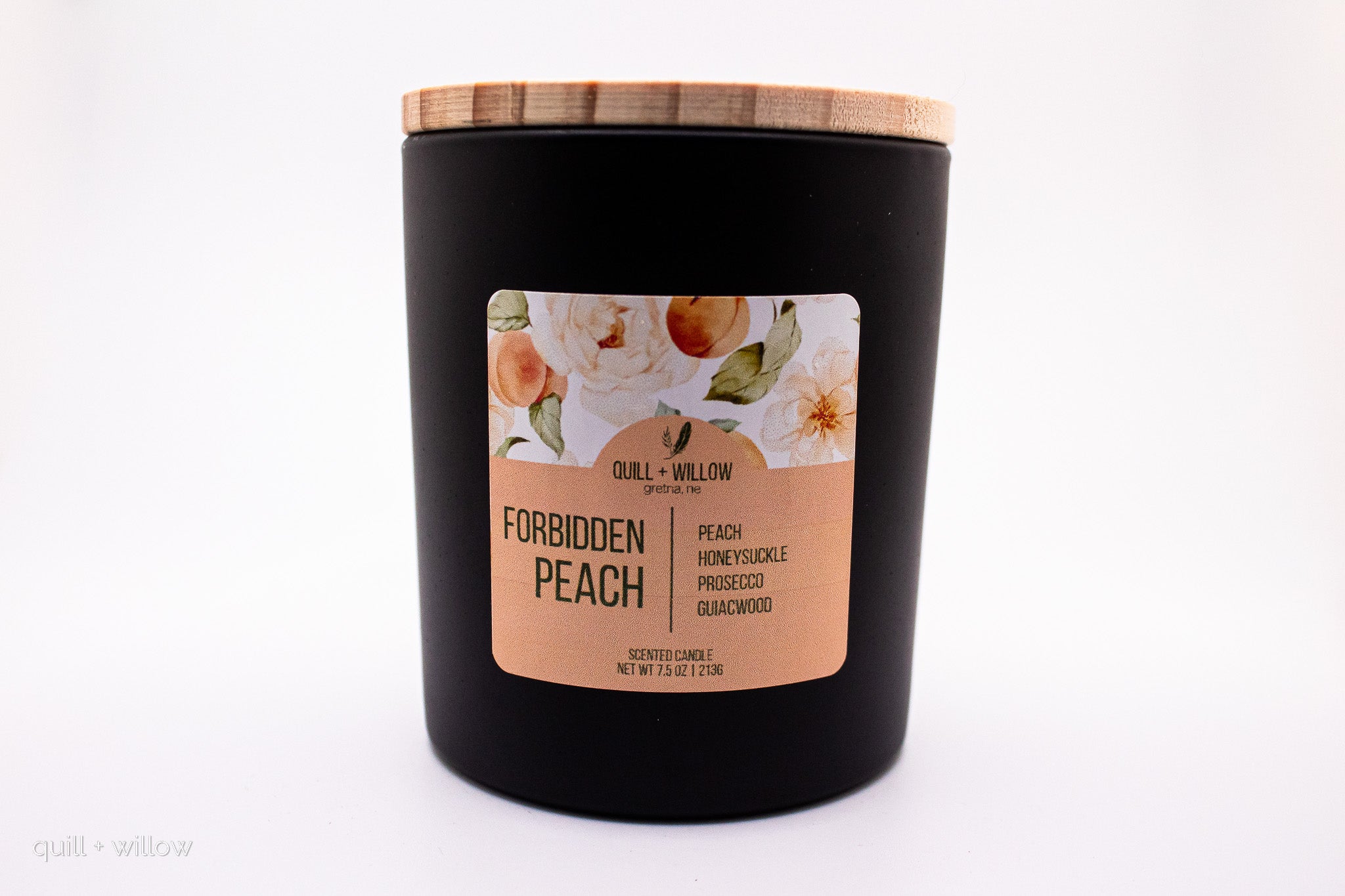 Black candle with a wooden lid and floral label on a white background