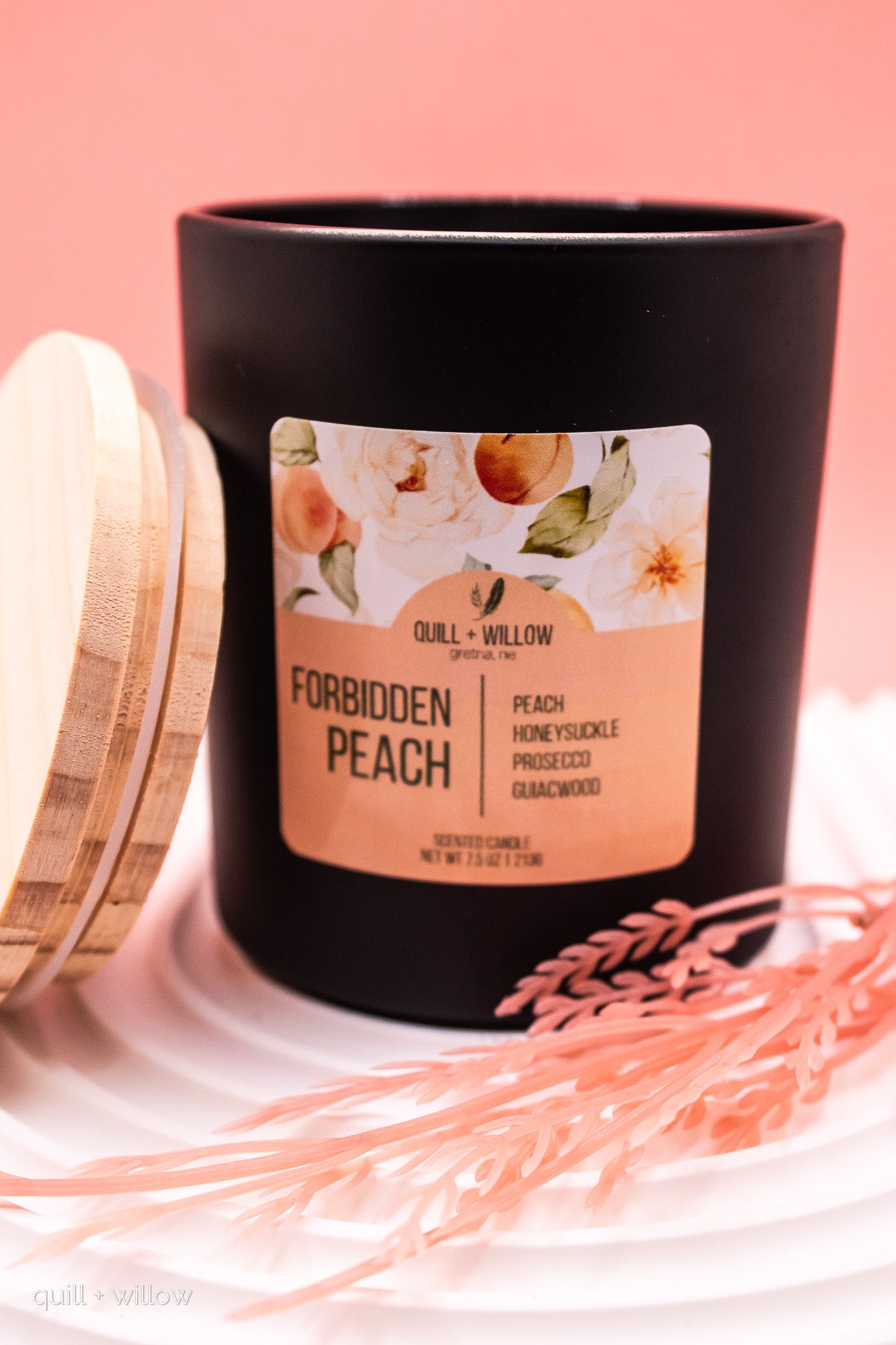 Black candle with a 'Forbidden Peach' label on a pink background