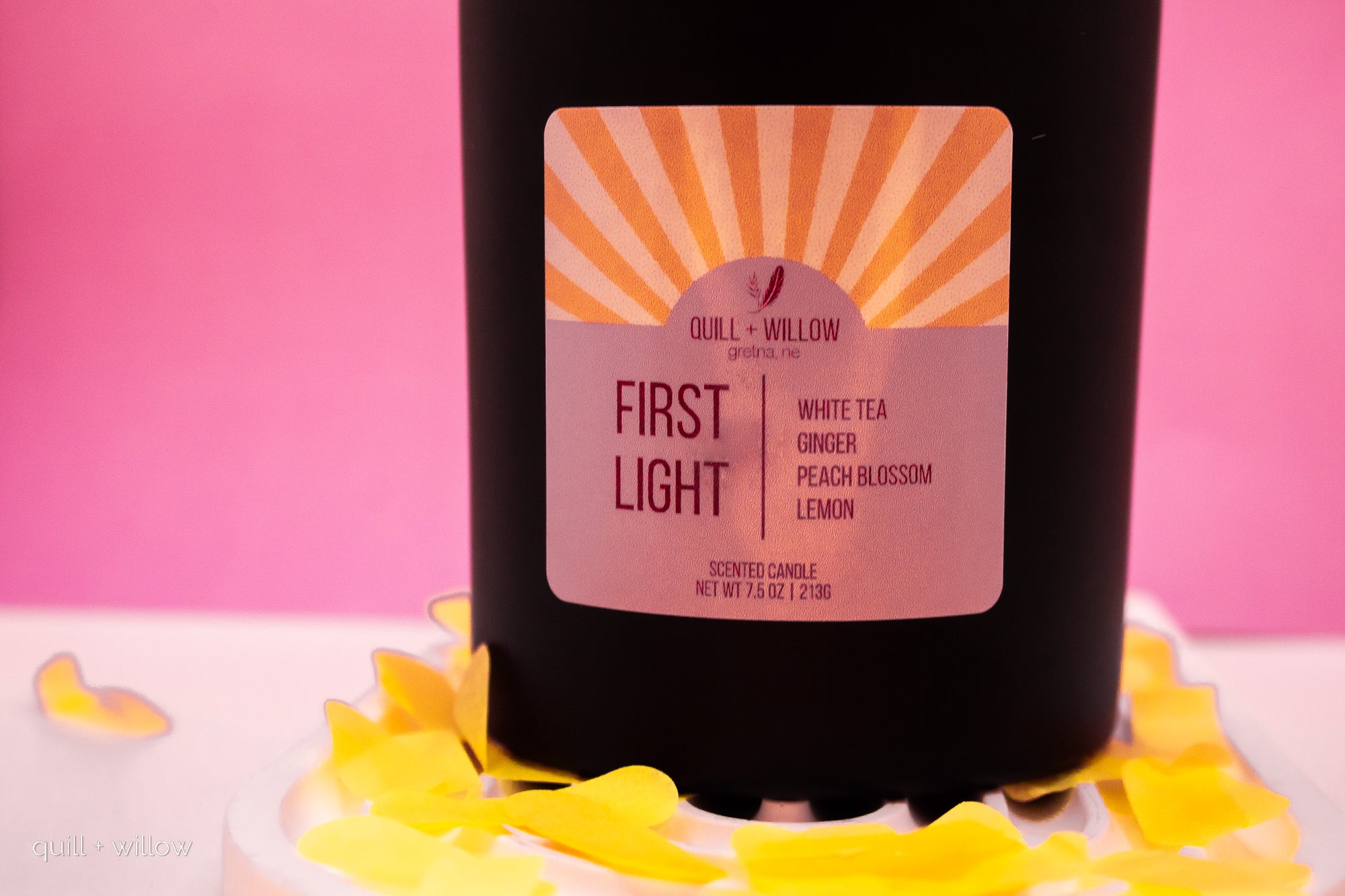 Black candle with a label on a pink background