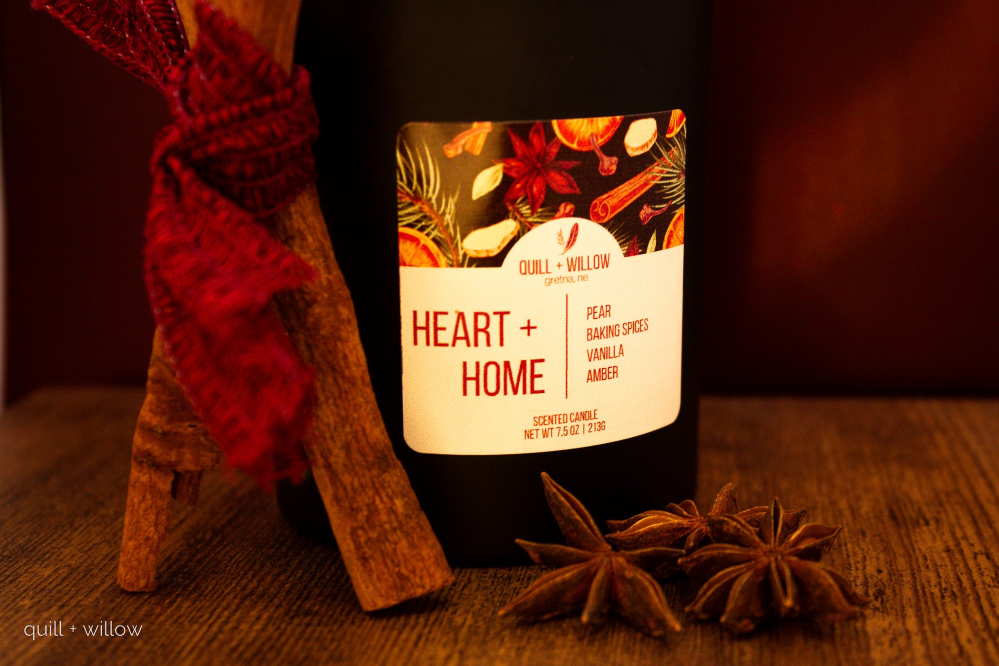 Candle with 'Heart + Home' label and decorative elements on a wooden surface