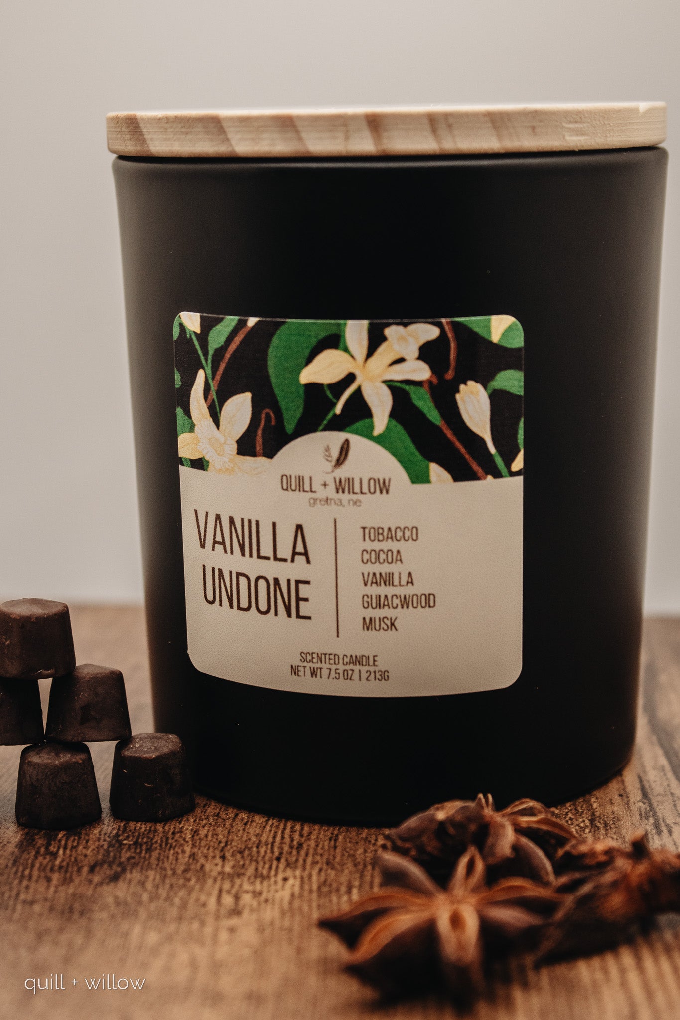 Black candle with a floral label on a wooden surface