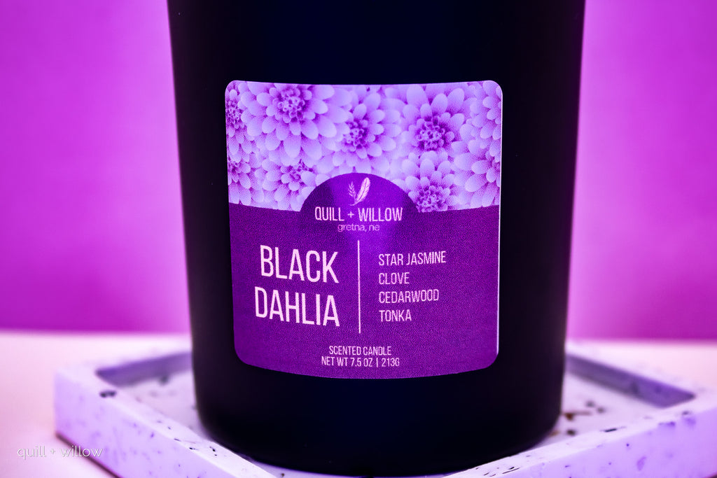 Black candle with a purple label on a purple background