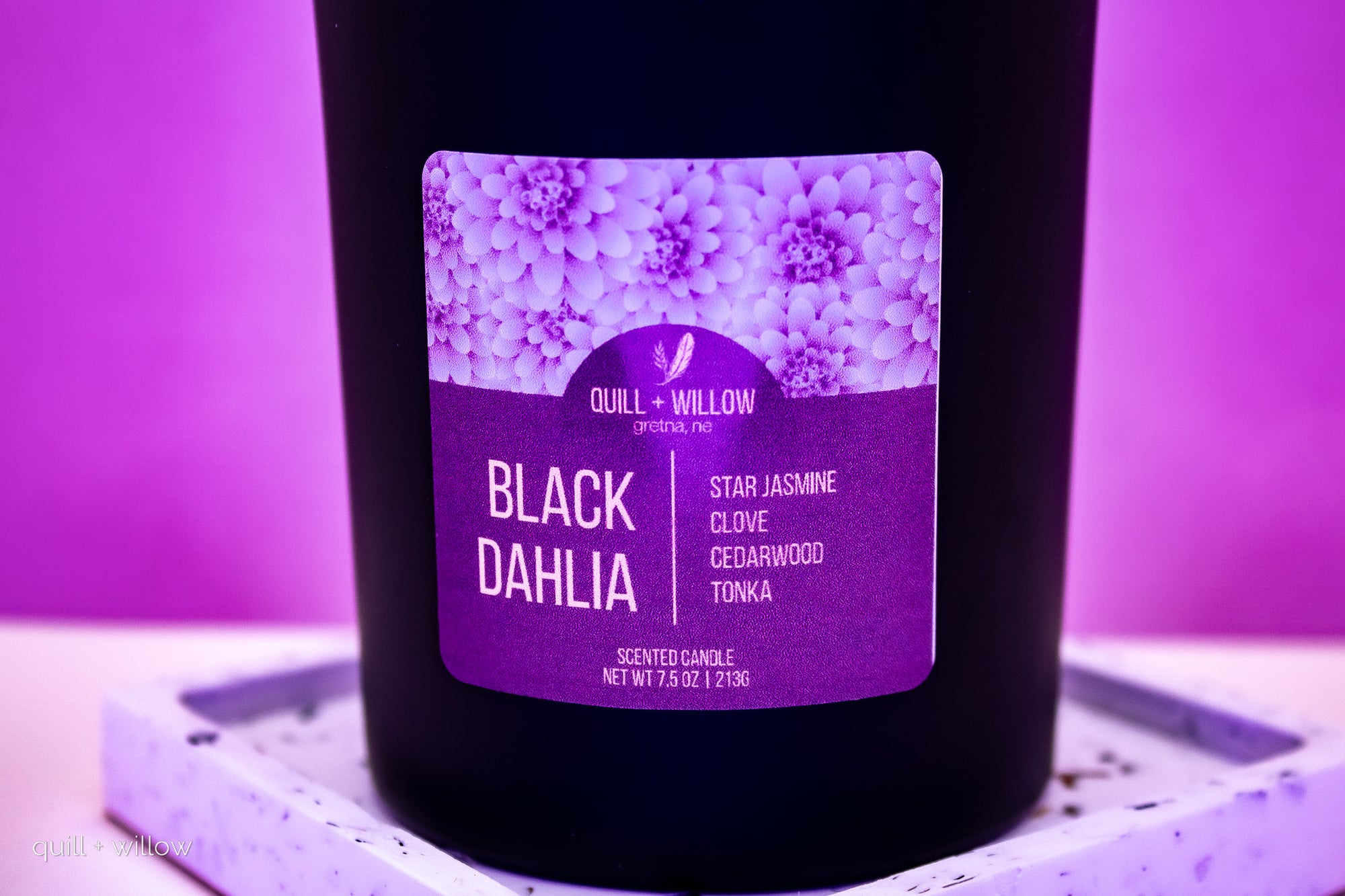Black candle with a purple label on a purple background
