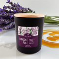 Black candle labeled 'London Fog' with lavender and honey on a white surface
